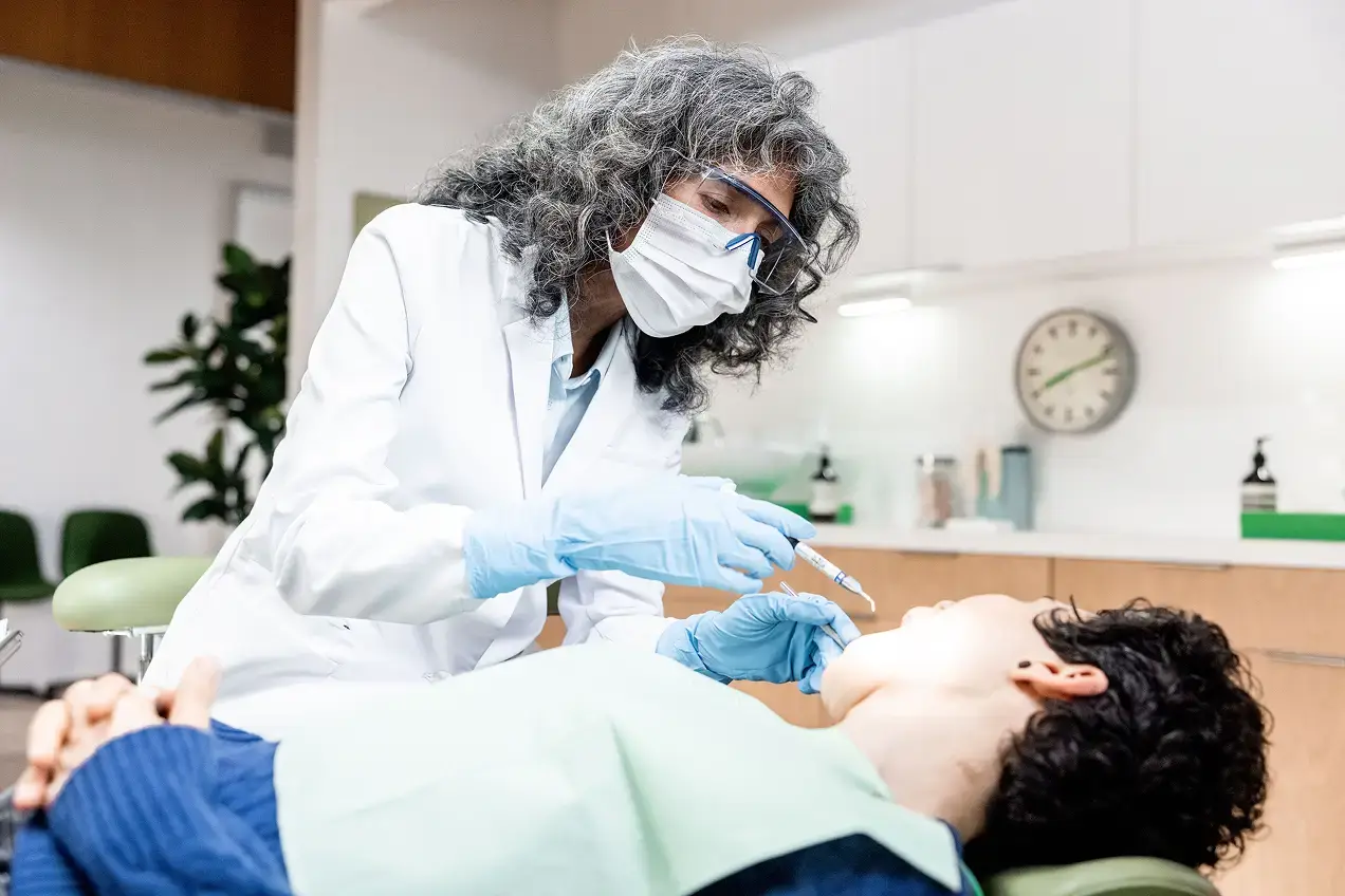 A dentist wearing a mask, face shield, and gloves prepares to give an injection to a patient in a modern clinic, highlighting the importance of healthcare marketing in promoting safe and advanced dental care.