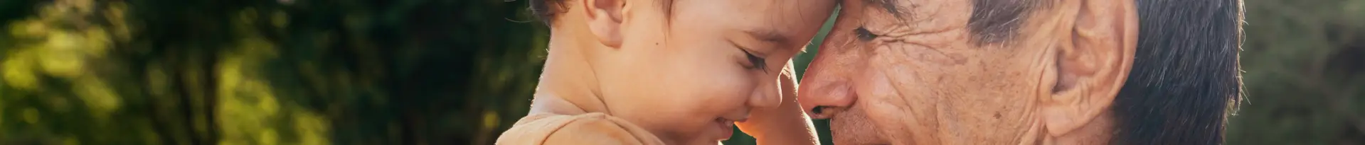 A young child and an older adult touch foreheads tenderly outdoors, both with eyes closed and gentle smiles, sharing a moment of affection that reflects the connections fostered by thoughtful consumer health marketing.