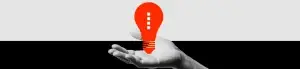 A grayscale hand is shown palm up against a divided black and white background, holding a bright red, stylized light bulb—a striking visual for pharma marketing or healthcare marketing campaigns seeking bold, innovative appeal.