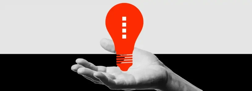 A grayscale hand is shown palm up against a divided black and white background, holding a bright red, stylized light bulb—a striking visual for pharma marketing or healthcare marketing campaigns seeking bold, innovative appeal.
